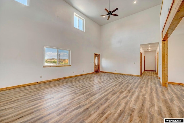 unfurnished living room with ceiling fan, high vaulted ceiling, and light hardwood / wood-style floors