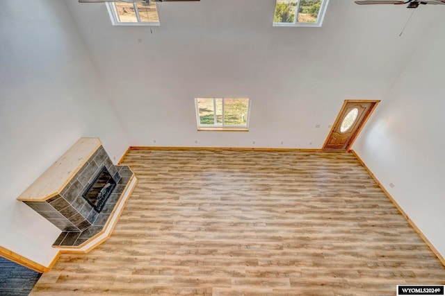 living room with ceiling fan, a towering ceiling, and light wood-type flooring