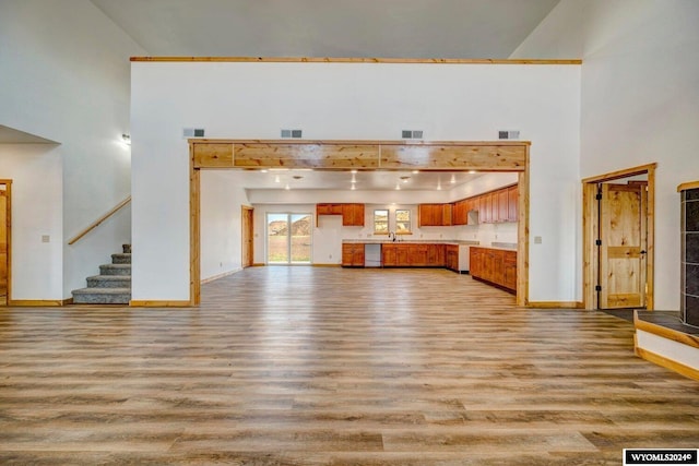 unfurnished living room featuring light hardwood / wood-style flooring, high vaulted ceiling, and sink