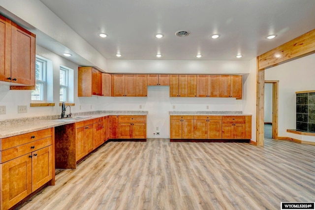 kitchen with beam ceiling, sink, and light wood-type flooring