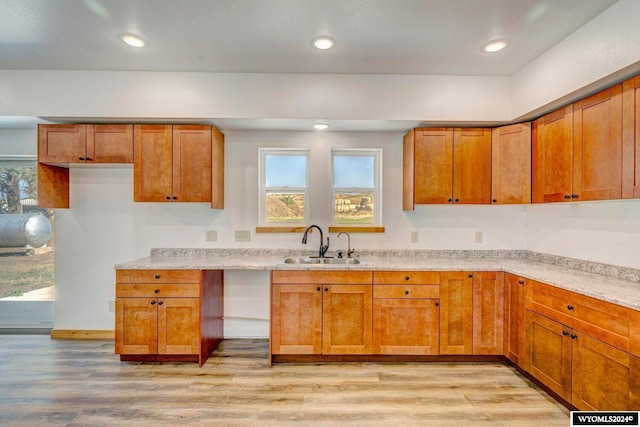 kitchen featuring light stone counters, sink, and light hardwood / wood-style flooring