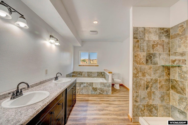 bathroom with vanity, a relaxing tiled tub, toilet, and wood-type flooring