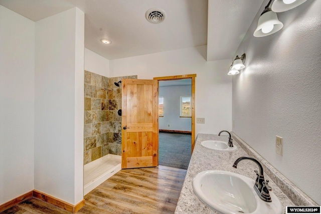 bathroom with vanity, wood-type flooring, and tiled shower