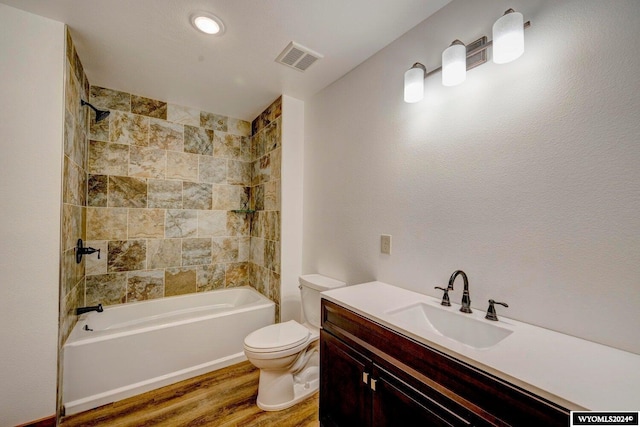 full bathroom featuring hardwood / wood-style flooring, vanity, toilet, and tiled shower / bath