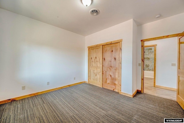 unfurnished bedroom with dark carpet and a closet