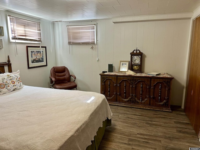 bedroom featuring dark hardwood / wood-style flooring and wooden walls