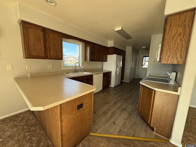 kitchen featuring sink, dark hardwood / wood-style floors, kitchen peninsula, a textured ceiling, and white appliances