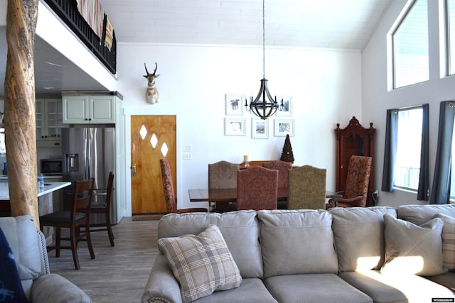 living room featuring crown molding, a towering ceiling, a notable chandelier, and hardwood / wood-style flooring