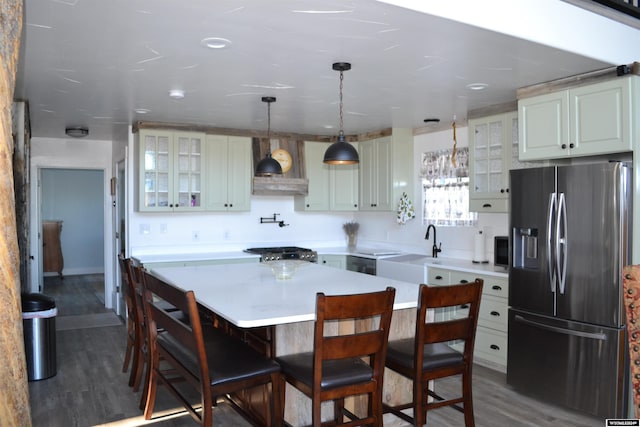 kitchen with appliances with stainless steel finishes, dark hardwood / wood-style flooring, a breakfast bar, sink, and a center island