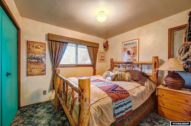 bedroom with dark colored carpet and a textured ceiling