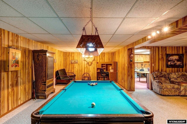 rec room with carpet, a drop ceiling, and wood walls