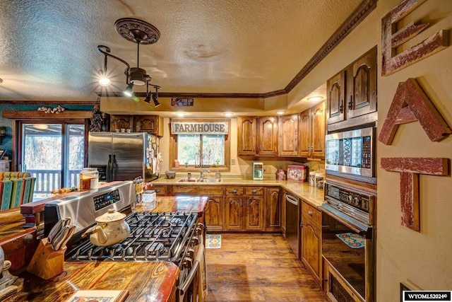 kitchen with sink, light wood-type flooring, ornamental molding, a textured ceiling, and appliances with stainless steel finishes