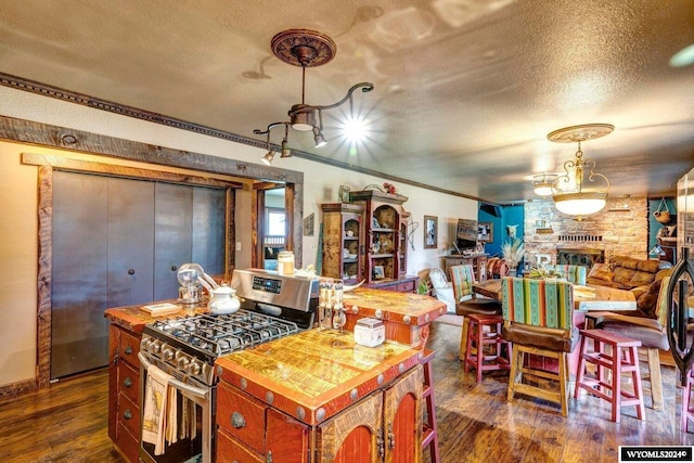 kitchen featuring dark hardwood / wood-style flooring, a center island, a textured ceiling, and stainless steel gas range oven