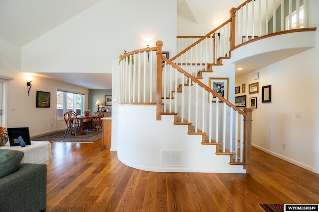 staircase featuring high vaulted ceiling and hardwood / wood-style flooring