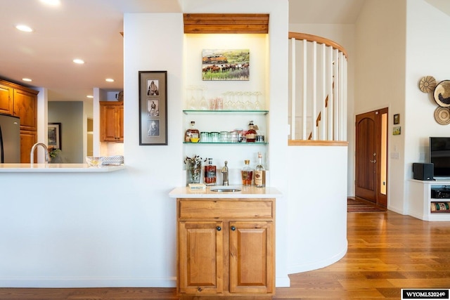 bar featuring dark hardwood / wood-style floors, stainless steel refrigerator, and sink