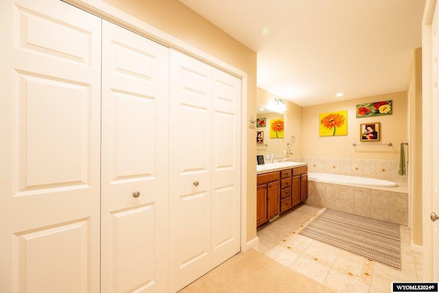 bathroom with tile patterned floors, vanity, and a relaxing tiled tub