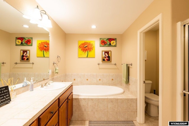 bathroom featuring tile patterned floors, vanity, a relaxing tiled tub, and toilet