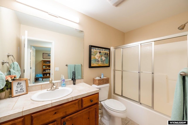 full bathroom with tile patterned floors, toilet, combined bath / shower with glass door, and vanity