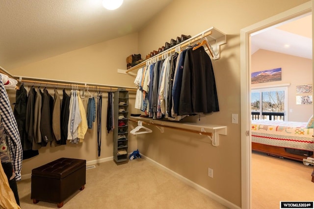 walk in closet featuring light colored carpet and vaulted ceiling