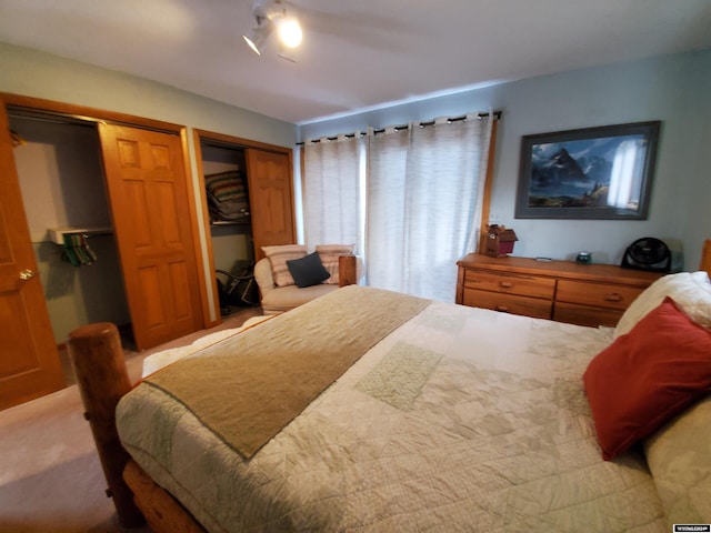 bedroom featuring multiple closets, ceiling fan, and light colored carpet