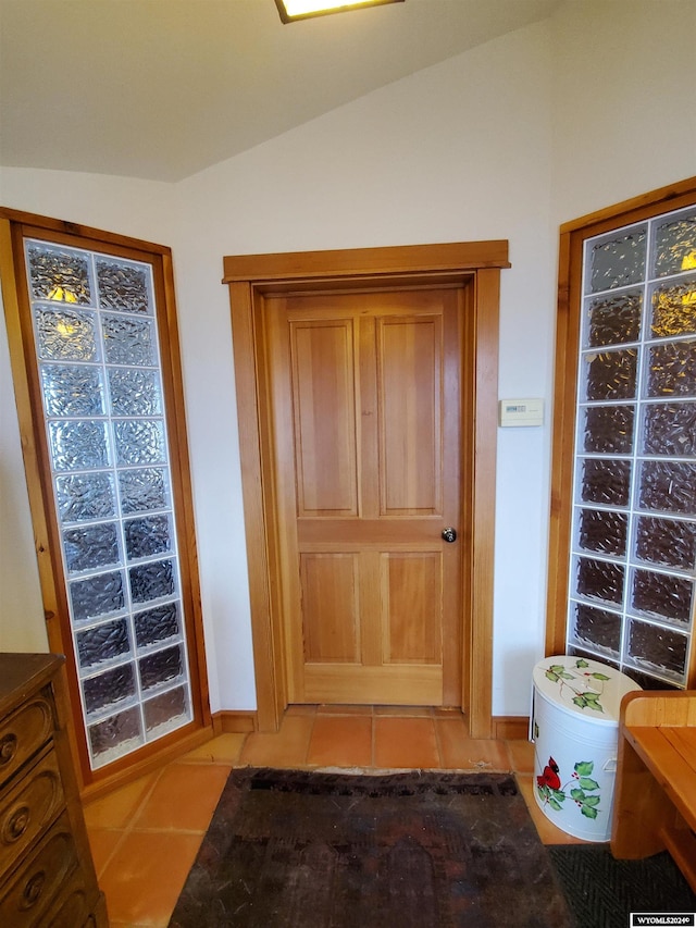 doorway with light tile patterned flooring and lofted ceiling