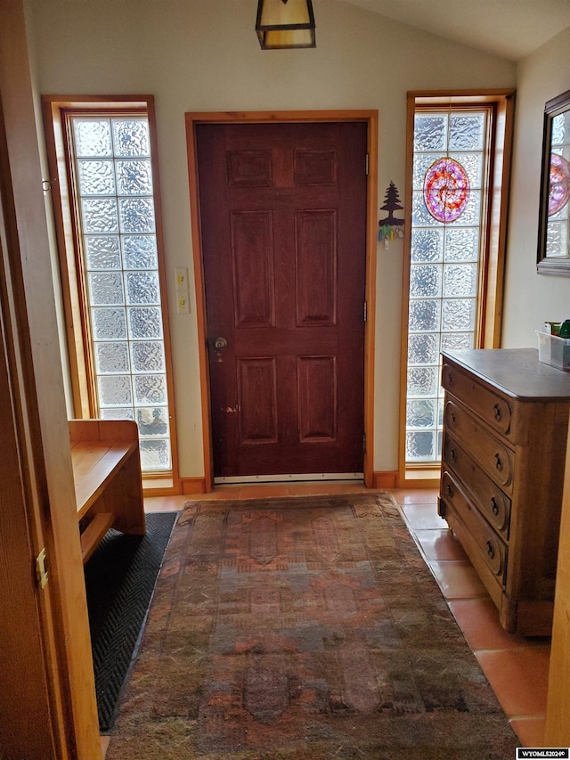 foyer featuring a wealth of natural light, light tile patterned flooring, and vaulted ceiling