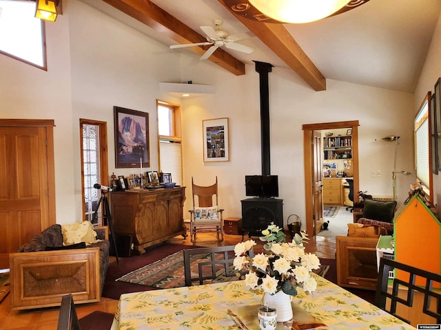 dining space with beam ceiling, a wood stove, ceiling fan, and high vaulted ceiling