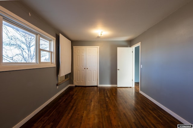 unfurnished bedroom with dark hardwood / wood-style floors and a closet