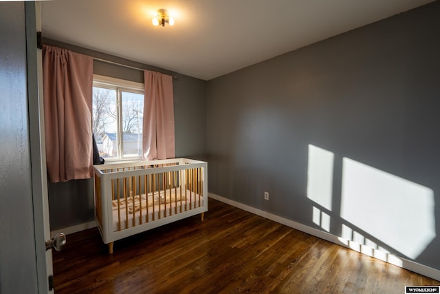 unfurnished bedroom with dark hardwood / wood-style flooring and a nursery area