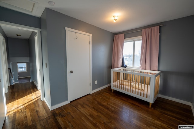 unfurnished bedroom featuring dark wood-type flooring, a closet, and a nursery area