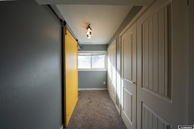 corridor with a barn door and light colored carpet