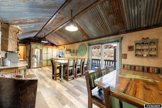 dining space featuring vaulted ceiling with beams and light wood-type flooring