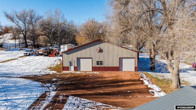 snow covered structure featuring a garage