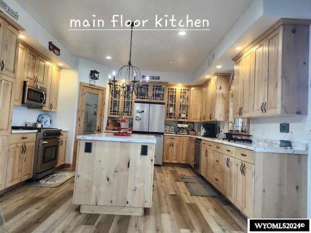 kitchen featuring appliances with stainless steel finishes, decorative light fixtures, an inviting chandelier, and light brown cabinetry