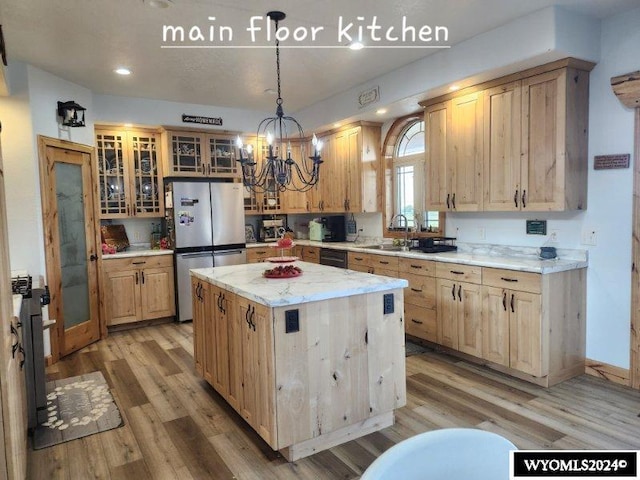 kitchen with stainless steel refrigerator, a center island, a chandelier, pendant lighting, and wood-type flooring