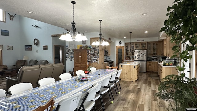 dining space featuring light hardwood / wood-style floors, a textured ceiling, and a chandelier