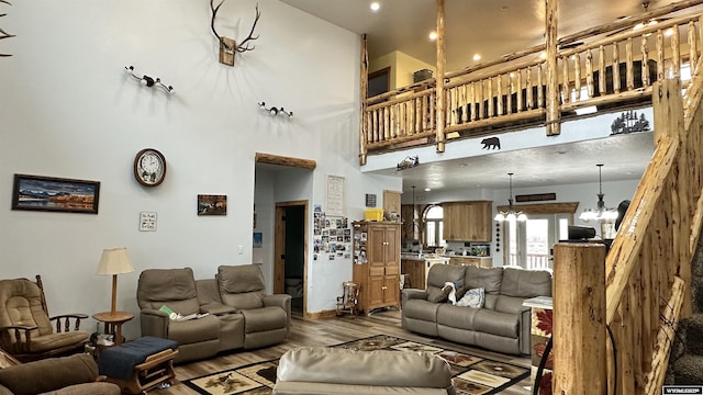 living room featuring wood-type flooring, a high ceiling, and an inviting chandelier