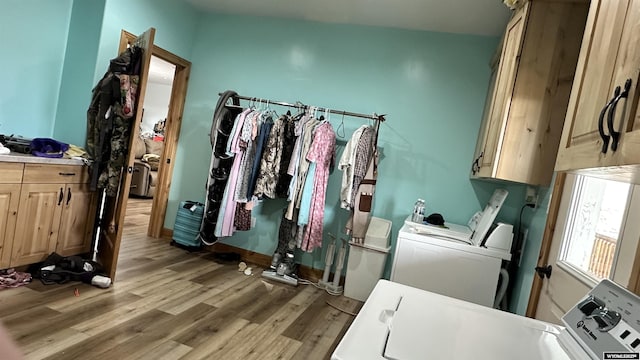 washroom featuring washer and dryer, light hardwood / wood-style floors, and cabinets