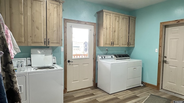 clothes washing area with washer and dryer, light hardwood / wood-style floors, and cabinets