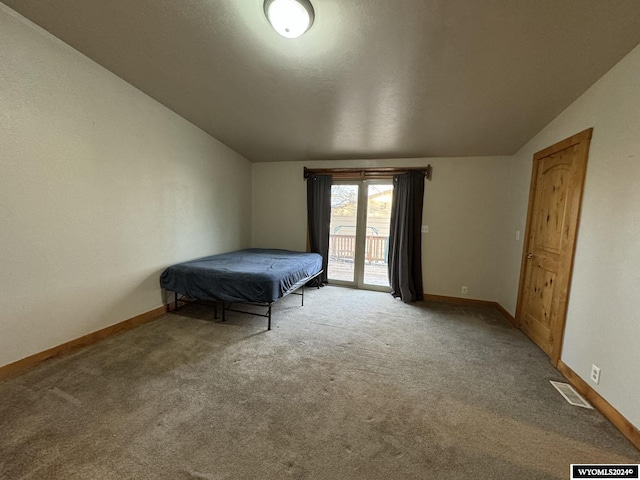 unfurnished bedroom with light carpet, access to outside, and vaulted ceiling