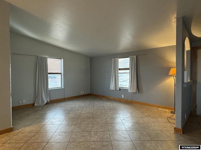 unfurnished room featuring light tile patterned flooring and vaulted ceiling