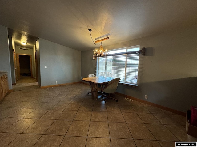 unfurnished dining area with dark tile patterned floors, vaulted ceiling, and an inviting chandelier