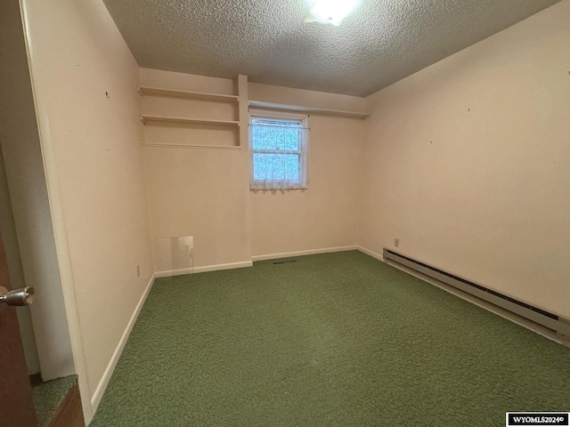 spare room with a baseboard heating unit, dark carpet, a textured ceiling, and baseboards