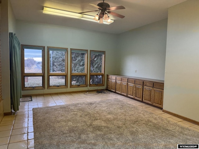 empty room featuring light tile patterned floors, ceiling fan, and baseboards