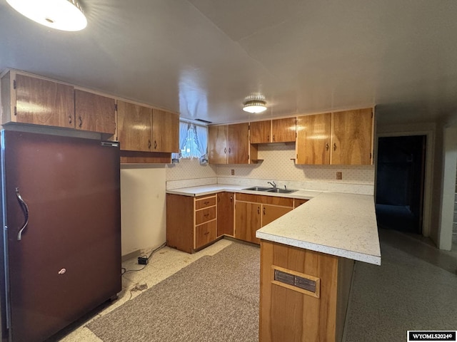 kitchen with visible vents, brown cabinets, freestanding refrigerator, light countertops, and a sink