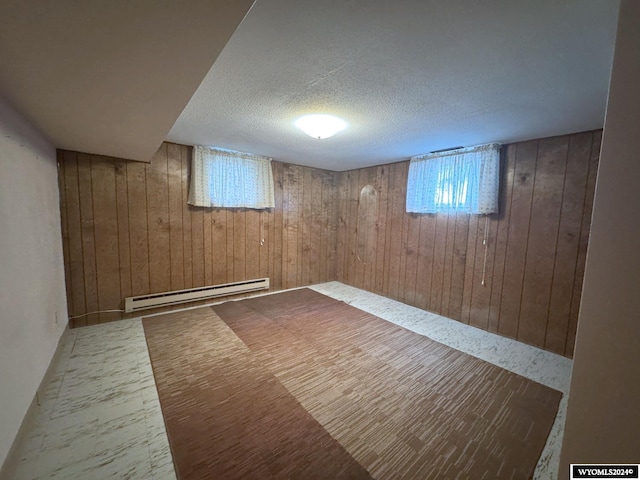 basement with a baseboard radiator, wooden walls, and a textured ceiling