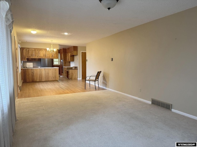 kitchen with baseboards, visible vents, white microwave, brown cabinets, and open floor plan