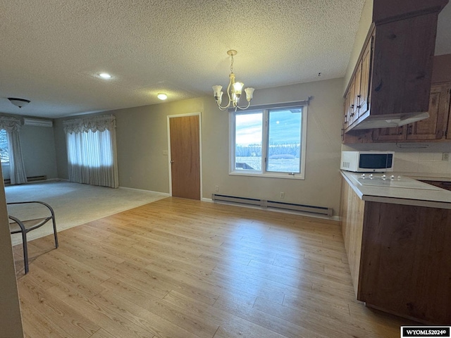 kitchen with light wood-style floors, a baseboard radiator, open floor plan, and an inviting chandelier