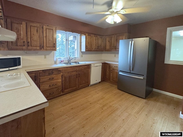 kitchen featuring light wood-type flooring, white appliances, brown cabinets, and a sink