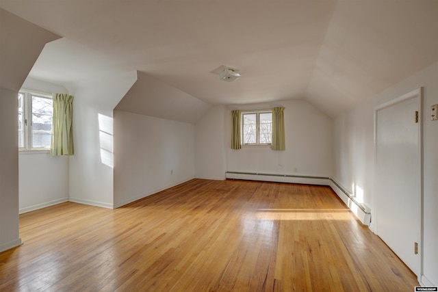 additional living space with light wood-type flooring, vaulted ceiling, and plenty of natural light